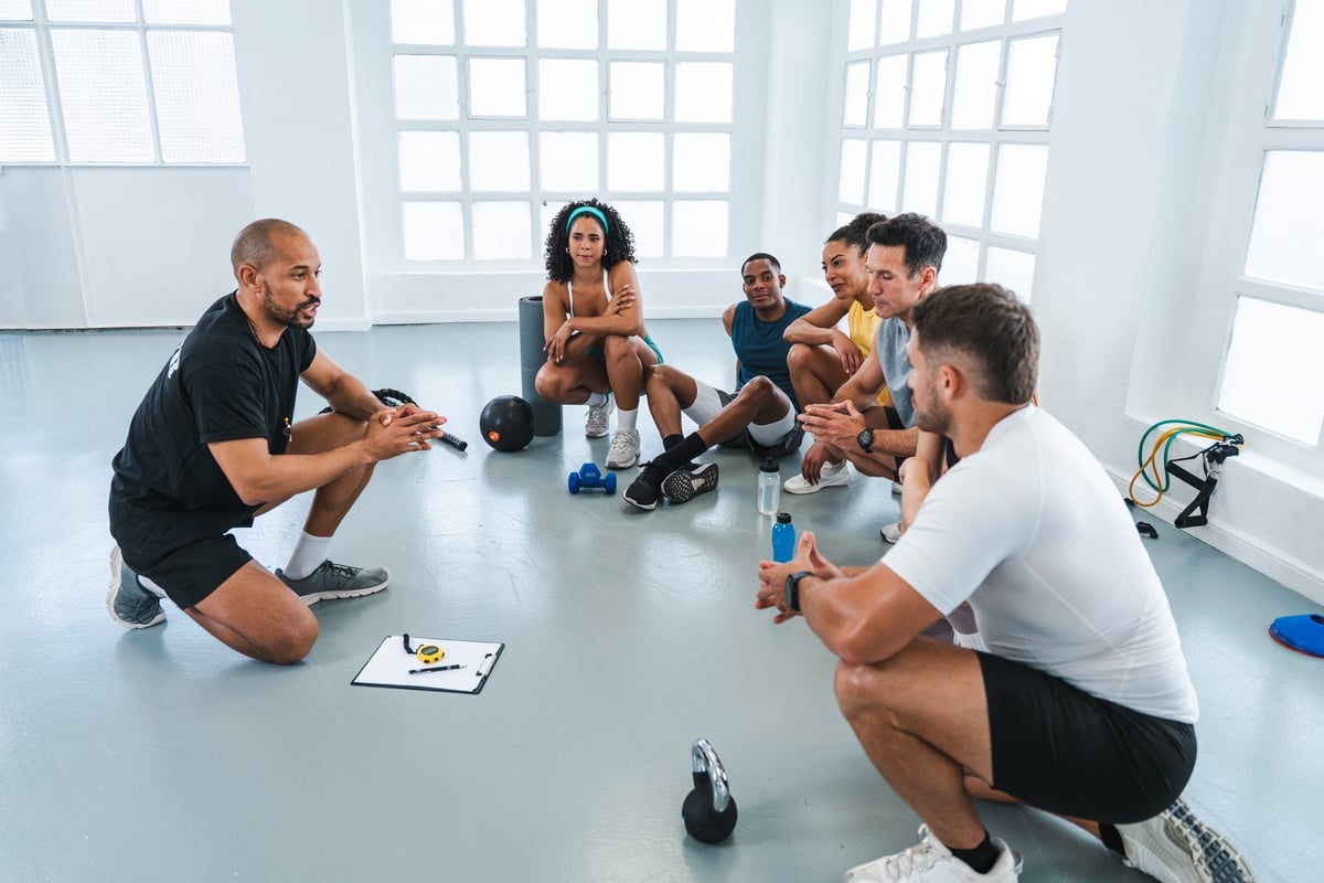 A group of fitness professionals in a training class being guided by two personal trainers