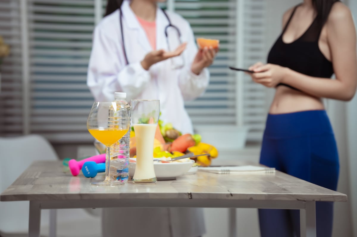 A health practitioner reviewing a nutrition and fitness plan with a client in a bright clinic office